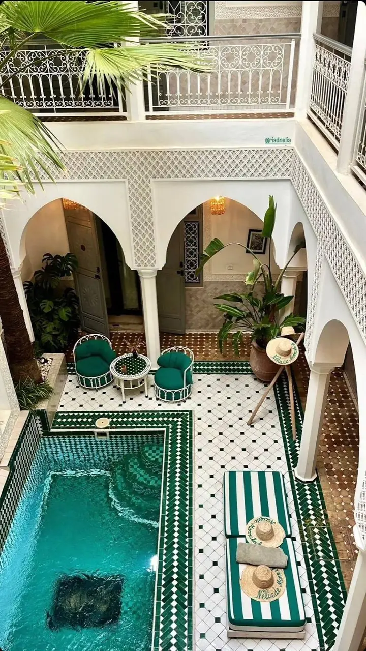 Traditional Marrakech riad courtyard with a green zellige pool and palm trees